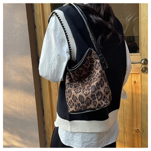Close-up of leopard print bucket bag with long shoulder strap in warm outdoor light