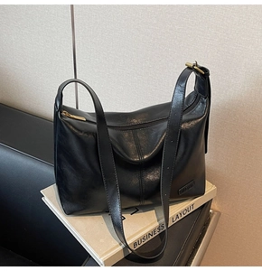 Détail du grand sac cabas noir en cuir avec fermeture éclair et plaque de marque en métal
