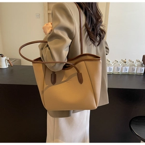 Detail of khaki pebbled leather tote bag with dark brown straps and gold brand lettering