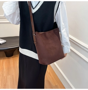 Detail view of large dark brown suede bucket bag with long shoulder strap in retro style