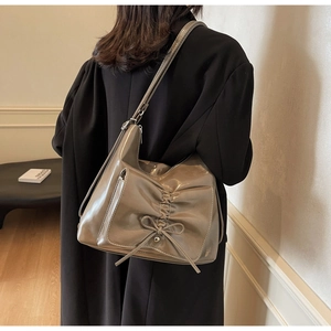 Detail of metallic shoulder bag with bow and pleated texture on model back view