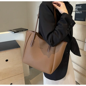 Close-up of brown litchi pattern leather tote with Fashion trend London text detail