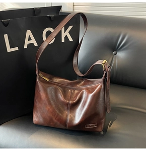 Détail d'un sac bandoulière en cuir marron avec finition vintage et sangle réglable
