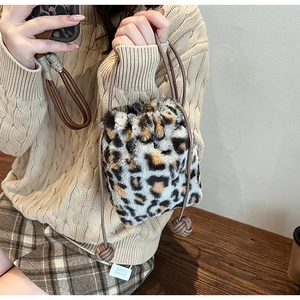 Detail of leopard print faux fur bucket bag featuring brown drawstring and woven knots