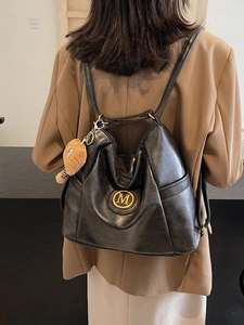 Retro black leather backpack for women featuring golden M logo and plush bear charm