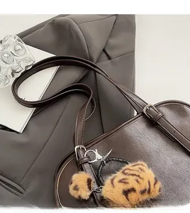 Détail d'un sac cabas marron foncé avec couture fine et breloque en peluche léopard