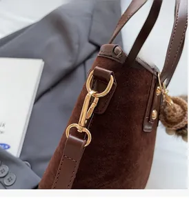 Détail du sac à main en daim marron avec boucles dorées et pompon décoratif doux