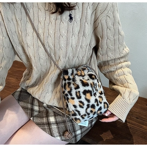 Detail of leopard print plush bucket bag with drawstring closure and leather strap
