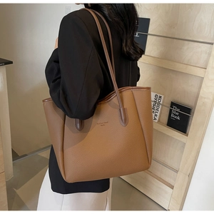 Detail of a brown lychee pattern leather tote bag with elegant long shoulder straps