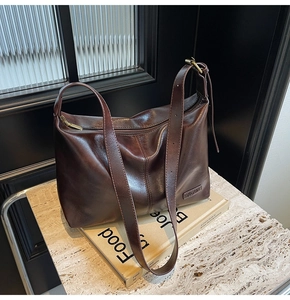 Détail du sac hobo en cuir marron foncé avec logo métallique et sangle réglable