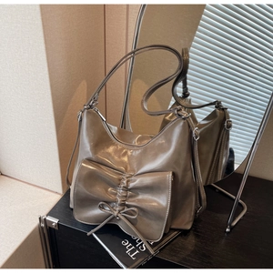 Detail of taupe faux leather shoulder bag with oversized pleated bow and glossy finish