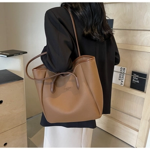 Detail of brown litchi pattern leather tote bag with long handles and minimalist logo