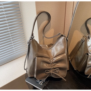 Detail of grey-brown tote bag featuring a pleated bow pocket and glossy leather texture