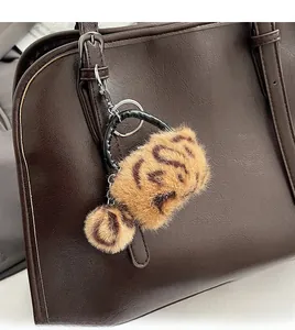 Détail d'un bijou de sac en peluche léopard avec pompon sur un sac à main en cuir