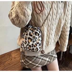 Detail shot of leopard print plush bucket bag with drawstring and woven knot accents
