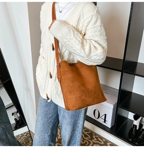 Brown faux suede bucket bag with adjustable strap worn with a cozy white cardigan