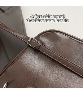 Détail de la bandoulière en cuir réglable avec boucle argentée sur sac marron