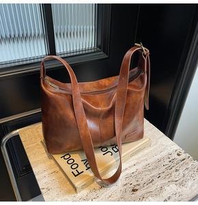 Détail d'un sac cabas marron vintage avec texture cuir et bandoulière réglable sur table