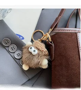 Gros plan du charm de sac monstre en peluche marron avec yeux blancs et bonnet tricoté