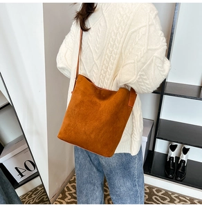 Detail view of brown faux suede bucket bag paired with a white knit sweater