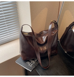 Détail d'un sac cabas vintage marron foncé avec fermeture éclair dorée et bandoulière