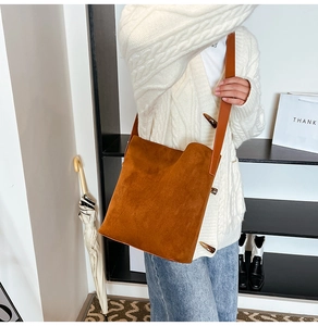 Close-up of brown suede bucket bag featuring horn toggle detail and leather shoulder strap