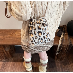 Detail of leopard print faux fur bucket bag with drawstring closure on model