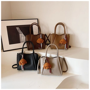 Détail de quatre sacs seaux en cuir grainé avec breloques d'ours en peluche et foulards en soie