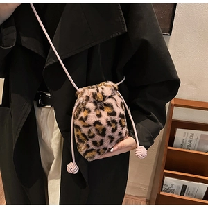 Close-up of pink leopard print plush drawstring bag with thin shoulder strap on black coat
