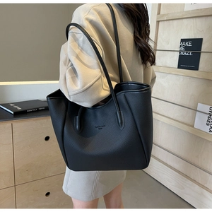 Detail of black pebbled leather tote bag with Fashion Trend text and shoulder strap