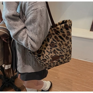 Detail view of large leopard print faux fur tote bag with brown leather handles