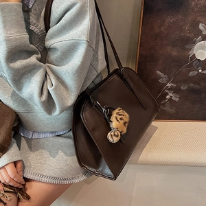 Détail du sac cabas en cuir marron foncé avec un charme pompon imprimé léopard chic