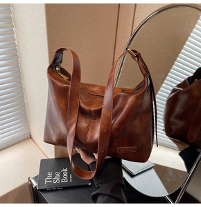 Détail de la bandoulière réglable et du zip d'un sac à main marron foncé brillant