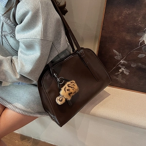Détail du sac cabas en cuir marron foncé avec un pendentif décoratif en peluche léopard