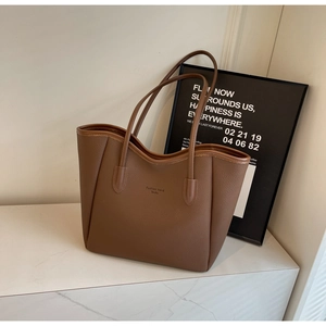 Close-up of brown pebbled leather tote bag with Fashion trend Souku logo on a marble surface