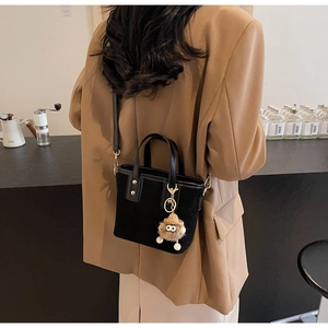 Détail du cabas noir en daim avec clous métalliques et breloque peluche monstre