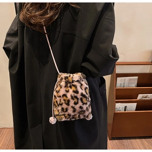 Leopard print plush bucket bag with pink drawstring strap shown on a model