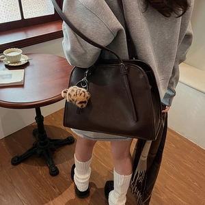 Détail d'un grand sac cabas marron foncé en similicuir avec charm pompon léopard à l'épaule