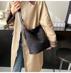 Woman in trench coat wearing a black suede bucket bag for casual everyday styling