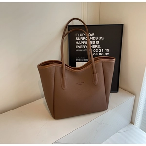 Close-up of brown lychee grain leather tote bag with embossed logo on marble surface