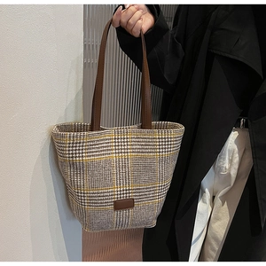Detail of vintage houndstooth pattern fabric and brown leather handle on a tote bag