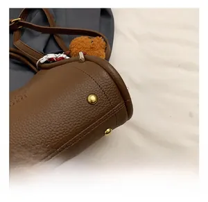 Detail of brown litchi pattern leather bucket bag with gold rivets and bear charm