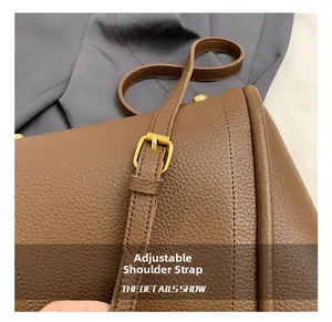 Detail of adjustable golden metal buckle and textured brown leather strap on bag