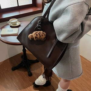Détail du cabas en similicuir marron foncé avec un pendentif peluche à motif léopard chic