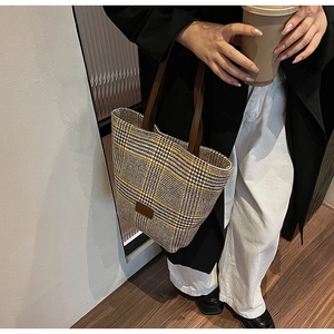 Macro view of textured houndstooth fabric and brown leather handle on a tote bag
