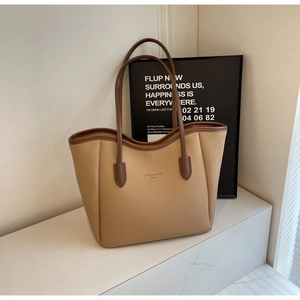 Detail of minimalist khaki tote bag with litchi grain leather and dark brown handles