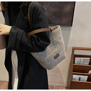 Detail of grey plaid plush tote bag with yellow accents and brown leather handles