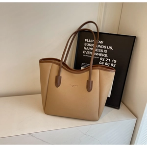 Detail of large beige tote bag with brown leather trim and pebble grain texture