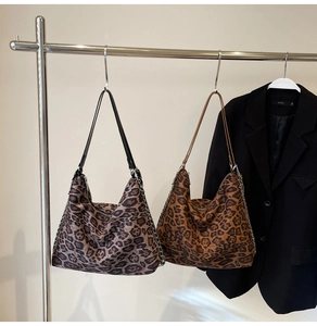 Detail of leopard print hobo bags with leather straps and silver chains hanging on a rack