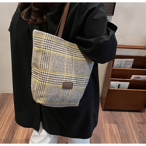 Dettaglio della borsa a secchiello vintage a quadri con tracolla in pelle marrone